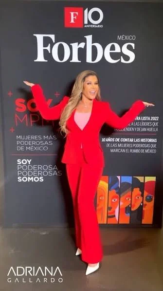 Adriana Gallardo in a red suit at Forbes México's 10th anniversary, in front of the 2022 Most Powerful Women of Mexico list